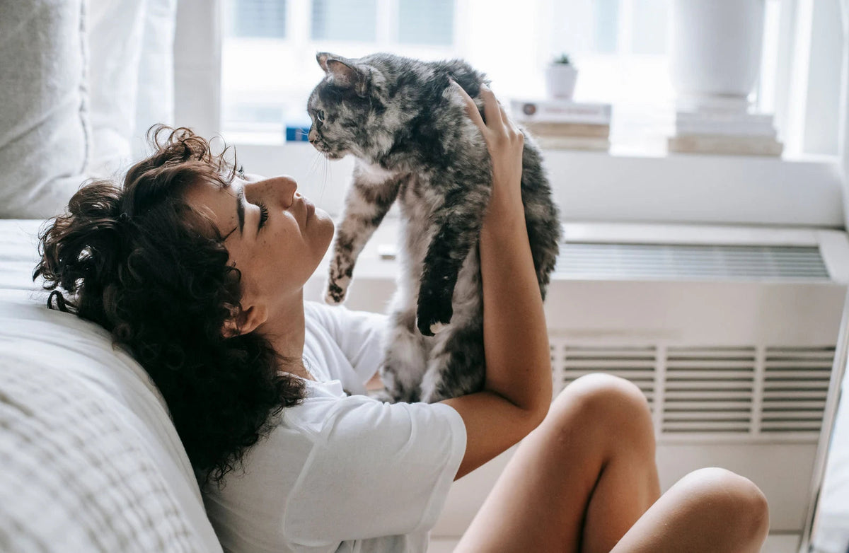 A woman cuddling her cat in a bright home. Photo by Sam Lion on Pexels.
